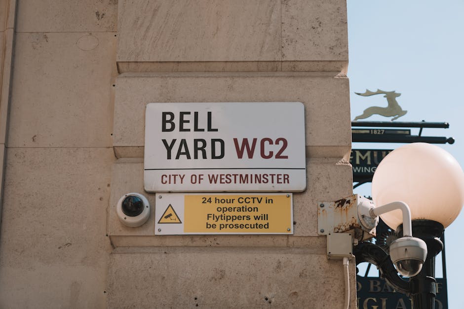 View of Westminster Station entrance with an underground roundel sign and a black and white sign indicating 'Westminster Station' with directions to public subway and toilets. A Union Jack flag is att